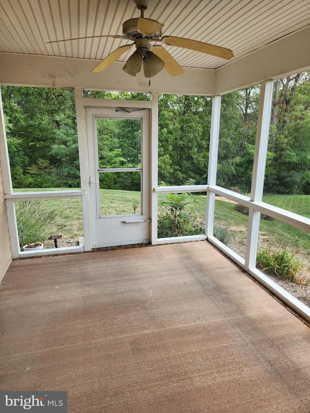 unfurnished sunroom featuring wooden ceiling, a wealth of natural light, and ceiling fan