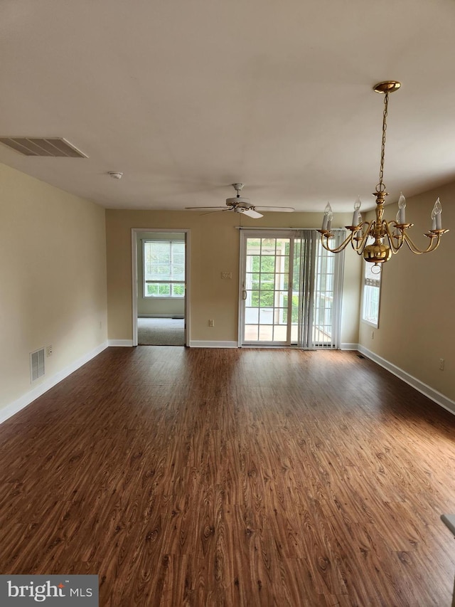 unfurnished living room featuring plenty of natural light, dark hardwood / wood-style floors, and ceiling fan with notable chandelier