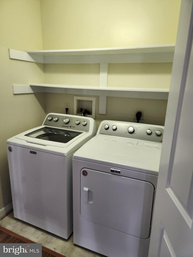 laundry room with washing machine and clothes dryer and light wood-type flooring