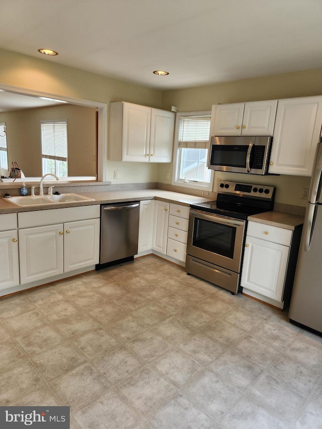 kitchen with appliances with stainless steel finishes, white cabinetry, and sink