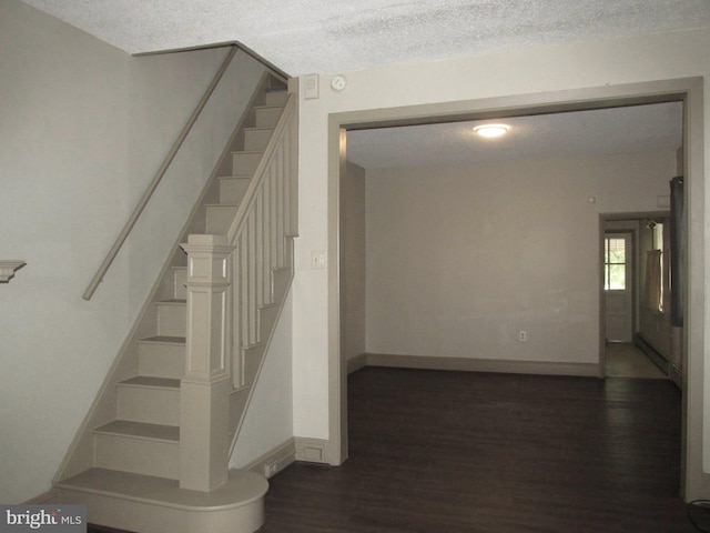 stairs featuring a textured ceiling and hardwood / wood-style floors