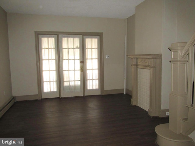 unfurnished living room with a baseboard heating unit and dark hardwood / wood-style floors