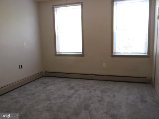 carpeted empty room featuring a baseboard heating unit and a healthy amount of sunlight