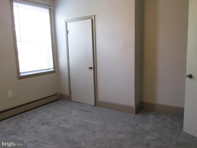 spare room with plenty of natural light, baseboard heating, and carpet floors