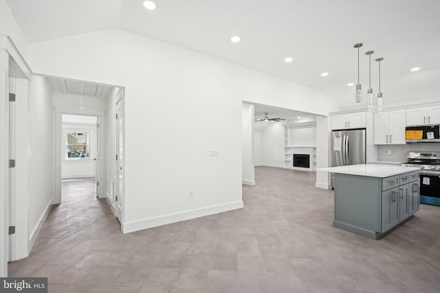 kitchen featuring a fireplace, lofted ceiling, gray cabinetry, appliances with stainless steel finishes, and a kitchen island