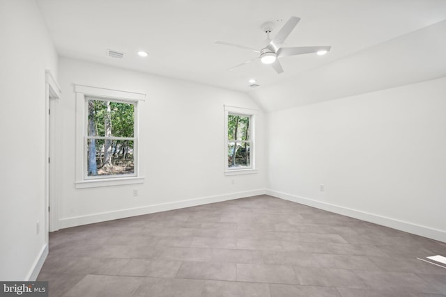 unfurnished room with a wealth of natural light, vaulted ceiling, and baseboards