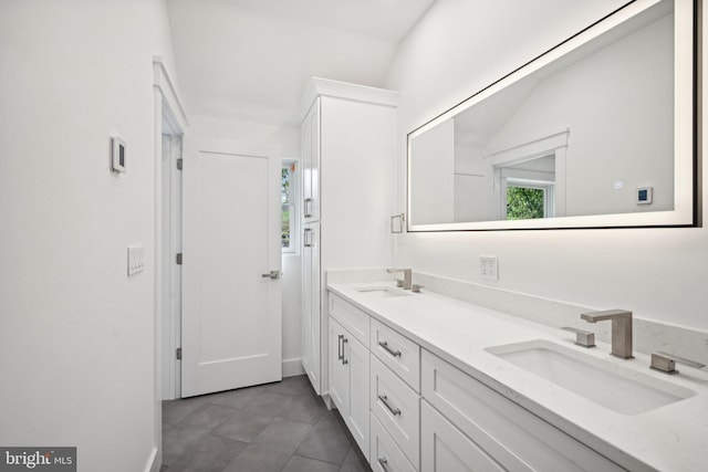 bathroom featuring tile patterned flooring, vaulted ceiling, and vanity