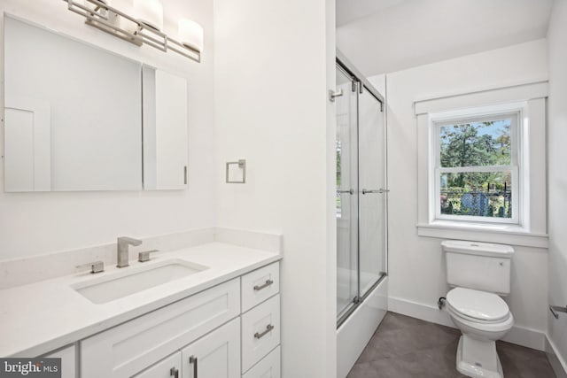 full bathroom featuring toilet, enclosed tub / shower combo, baseboards, and vanity