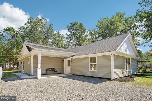 view of front of property with a patio, a shingled roof, and fence