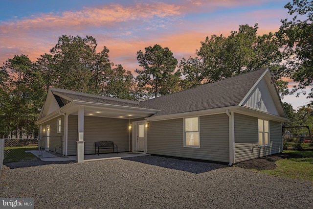 view of front facade featuring a shingled roof, a patio area, and fence