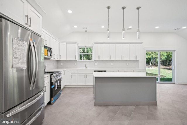 kitchen featuring white cabinets, a center island, stainless steel appliances, and vaulted ceiling