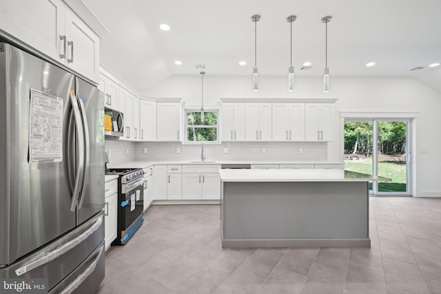 kitchen featuring appliances with stainless steel finishes, lofted ceiling, a sink, and backsplash