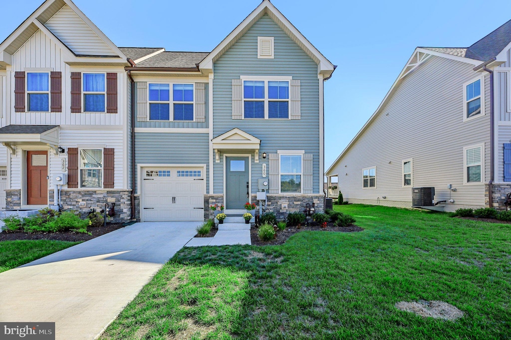 view of front of house with cooling unit, a garage, and a front lawn