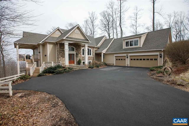 view of front of house with a garage, stone siding, and driveway