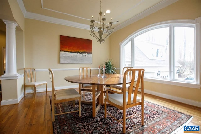 dining area featuring ornamental molding, light wood finished floors, decorative columns, and a notable chandelier