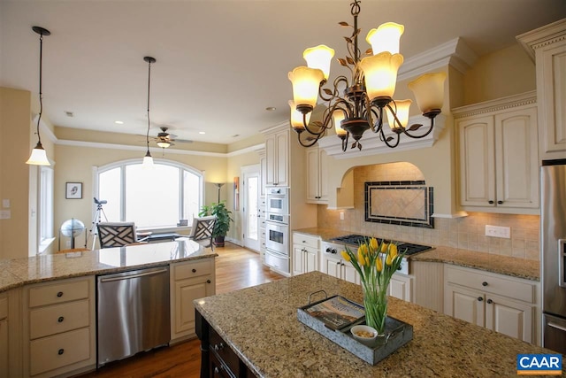 kitchen featuring tasteful backsplash, wood finished floors, stainless steel appliances, cream cabinetry, and pendant lighting