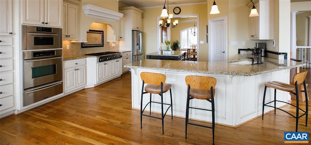 kitchen featuring light wood-style flooring, a sink, appliances with stainless steel finishes, a warming drawer, and tasteful backsplash