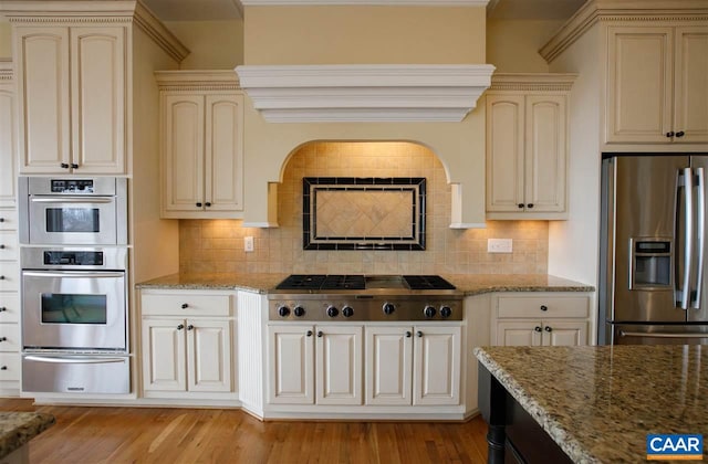 kitchen with cream cabinets, stainless steel appliances, a warming drawer, and light wood-style flooring