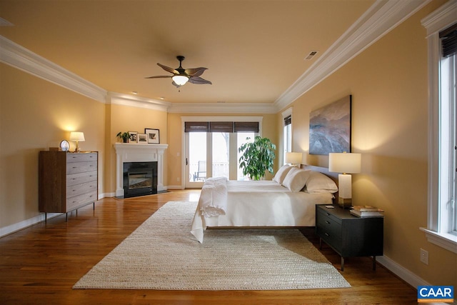 bedroom with ornamental molding, access to outside, a fireplace with flush hearth, and wood finished floors