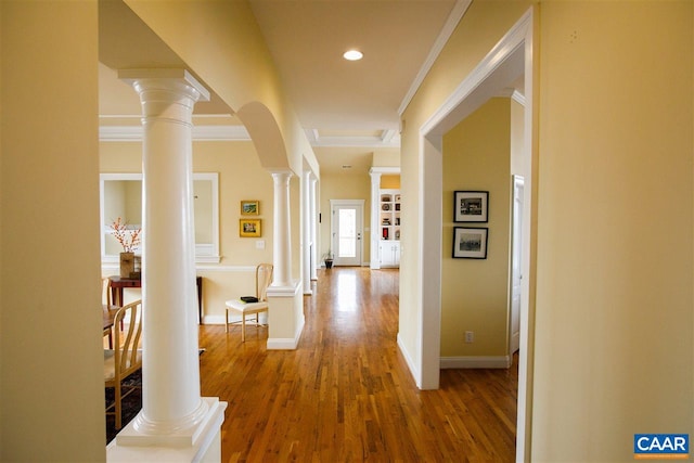 hall with arched walkways, recessed lighting, wood finished floors, baseboards, and ornate columns