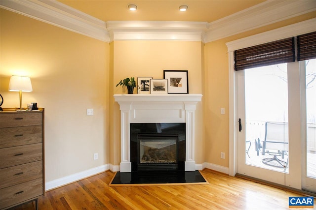 living room with a fireplace with flush hearth, crown molding, baseboards, and wood finished floors