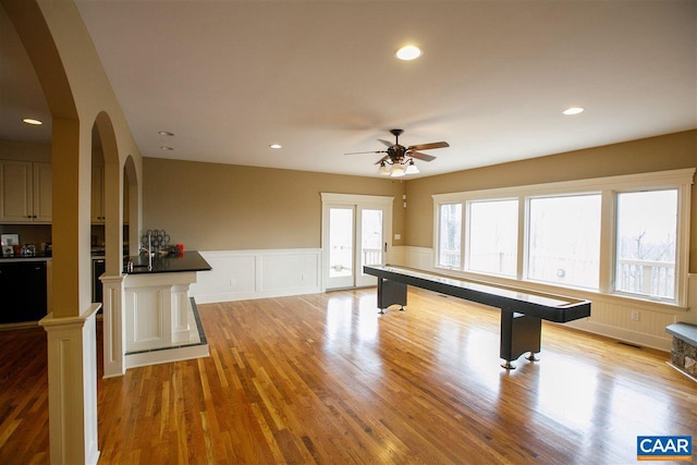 recreation room featuring arched walkways, recessed lighting, visible vents, wainscoting, and light wood-type flooring