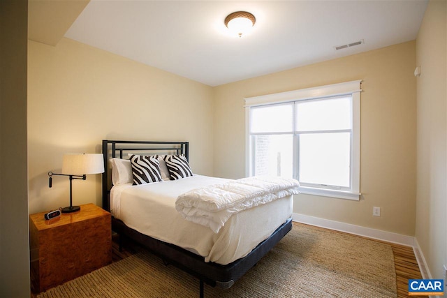 bedroom featuring baseboards, visible vents, and wood finished floors