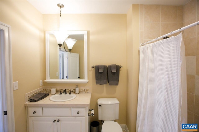 bathroom featuring toilet, tiled shower, and vanity