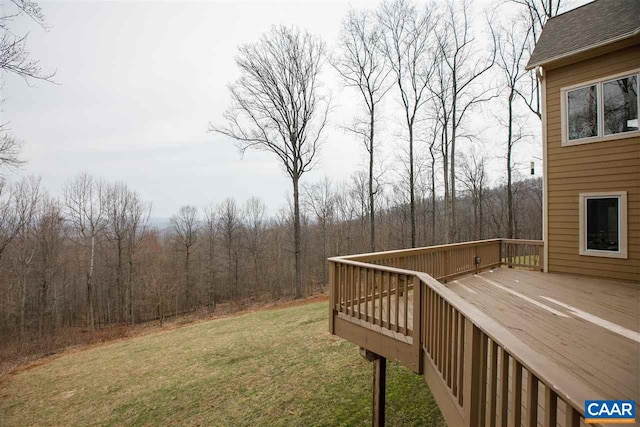 view of yard featuring a deck and a wooded view