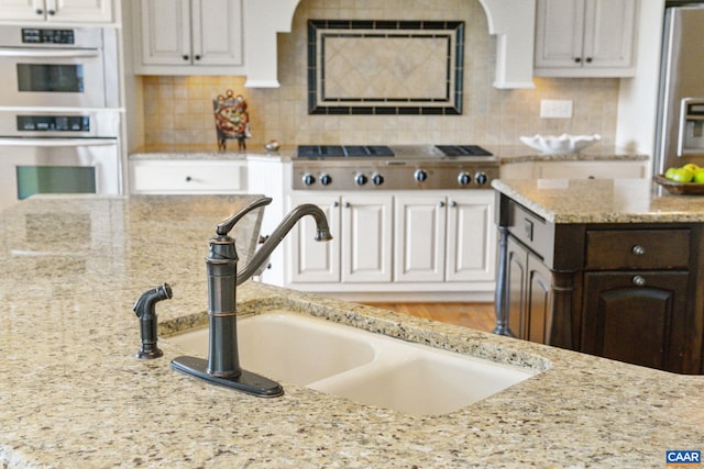 2515 Summit Ridge Trl, Charlottesville, VA 22911 - kitchen featuring appliances with stainless steel finishes, a sink, light stone countertops, decorative backsplash, and white cabinets