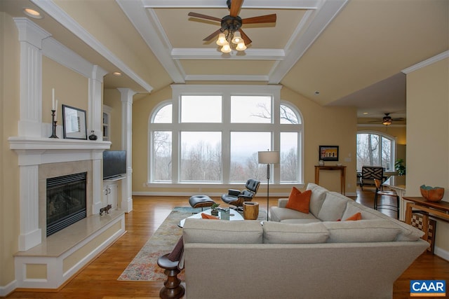 living room featuring vaulted ceiling with beams, a fireplace, light wood-style flooring, and ornate columns