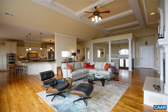 living area with light wood finished floors, decorative columns, visible vents, and beam ceiling