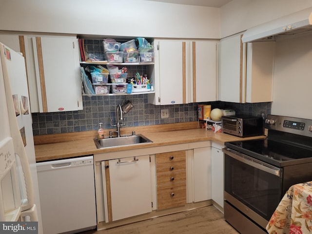 kitchen with a sink, under cabinet range hood, white appliances, a toaster, and decorative backsplash