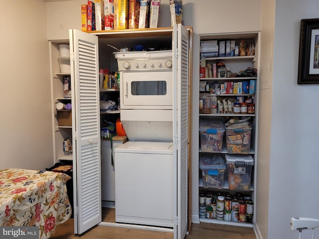 laundry room featuring laundry area, stacked washer and dryer, and wood finished floors