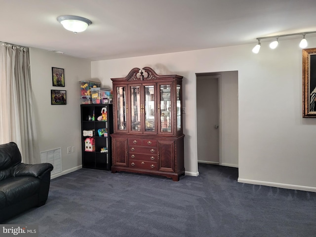 sitting room featuring track lighting, baseboards, visible vents, and dark carpet