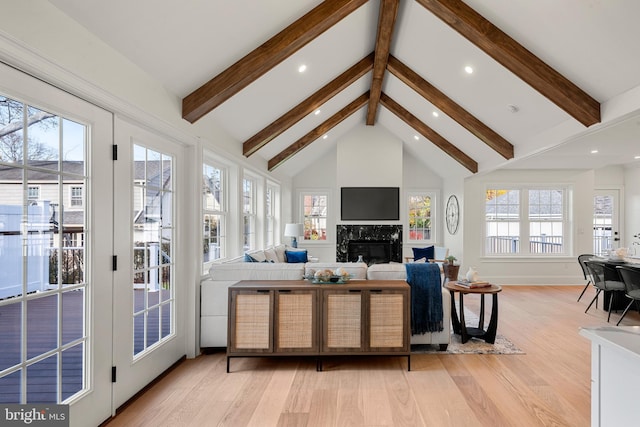 living room featuring plenty of natural light, beamed ceiling, light wood-type flooring, and high vaulted ceiling