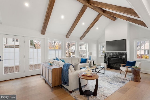 living room with light hardwood / wood-style floors, high vaulted ceiling, plenty of natural light, and a premium fireplace