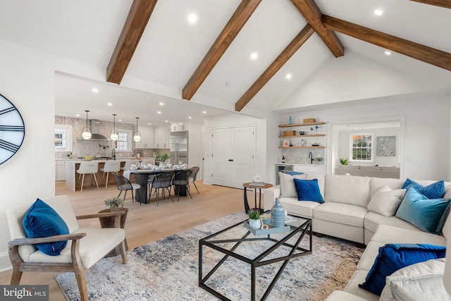 living room featuring beam ceiling, high vaulted ceiling, and light hardwood / wood-style flooring