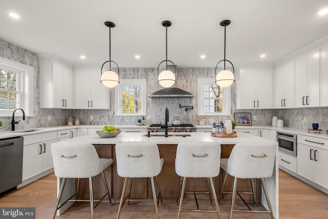 kitchen with sink, stainless steel dishwasher, an island with sink, decorative light fixtures, and white cabinets