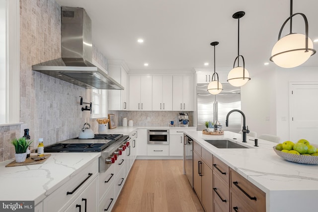 kitchen with pendant lighting, light stone countertops, white cabinets, and wall chimney range hood