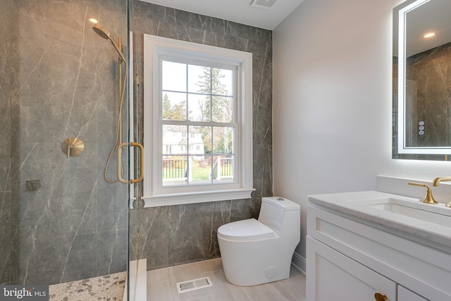 bathroom featuring tile patterned flooring, a tile shower, vanity, and toilet