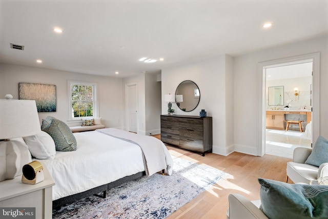 bedroom featuring connected bathroom and light hardwood / wood-style floors