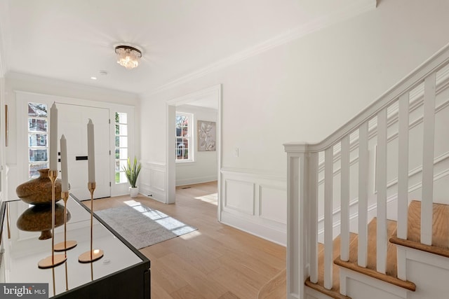 foyer with ornamental molding and light hardwood / wood-style flooring