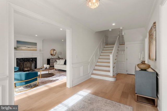 stairs with a high end fireplace, hardwood / wood-style flooring, and ornamental molding