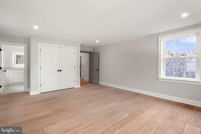 unfurnished bedroom with connected bathroom and light hardwood / wood-style floors