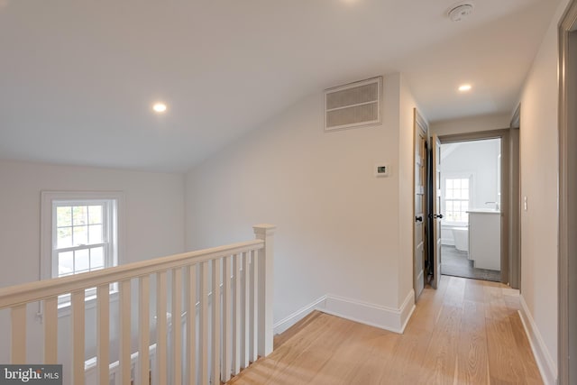 hall with plenty of natural light, light hardwood / wood-style floors, and vaulted ceiling