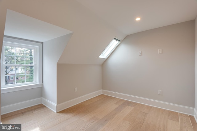 bonus room with lofted ceiling with skylight and light hardwood / wood-style flooring