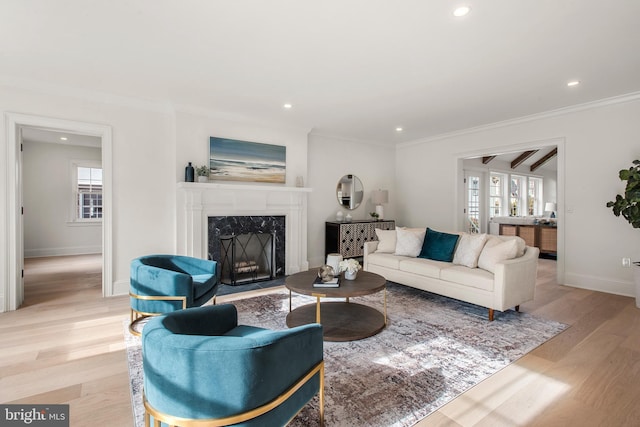 living room with a wealth of natural light, light hardwood / wood-style floors, ornamental molding, and a high end fireplace