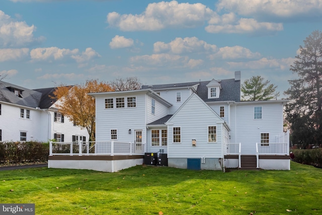 rear view of property with a lawn, a wooden deck, and central AC unit