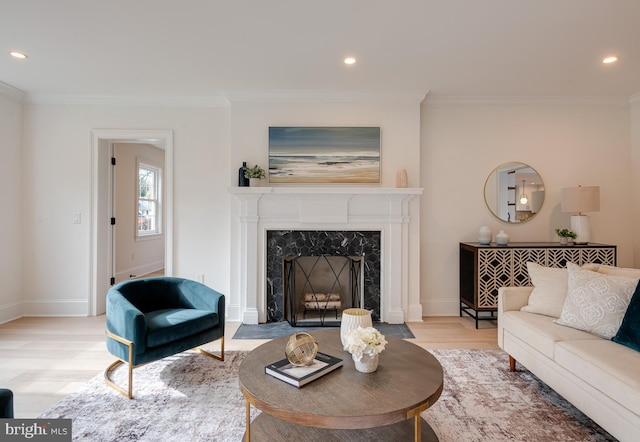 living room with a premium fireplace, ornamental molding, and light hardwood / wood-style flooring